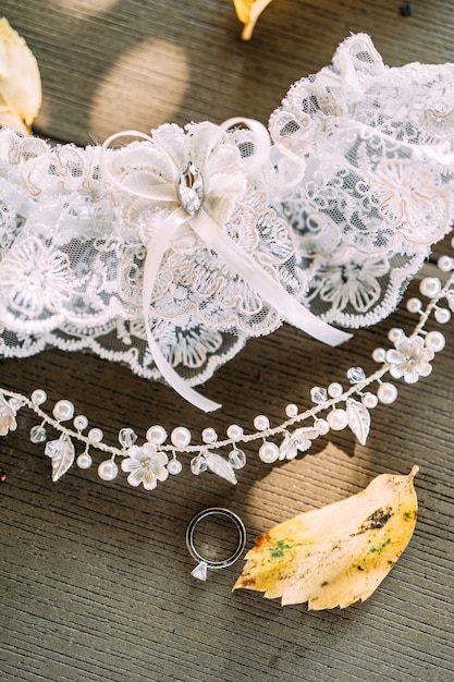 Foto diadema della giarrettiera della sposa sulla testa nell'anello nuziale dell'acconciatura sullo sfondo della trama di legno