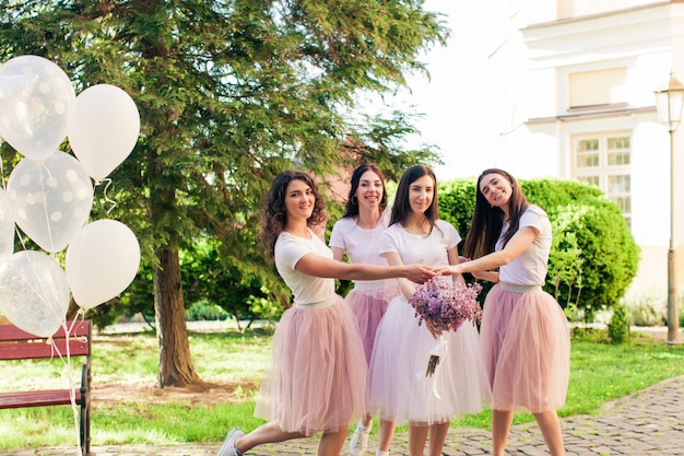 The bride and girlfriends are funny posing on the camera during the party in the park