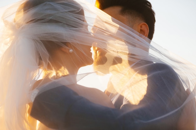 Bride and goom almost is kissing - close up image in the sunset light.