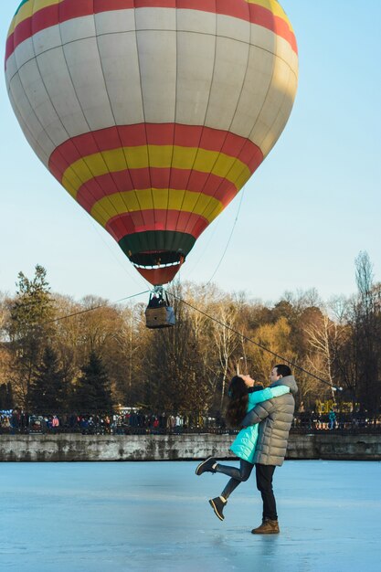 Sposa e sposo sullo sfondo di un lago ghiacciato e un palloncino che vola in un parco cittadino.