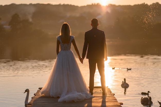 The bride and groom are in the back at sunset