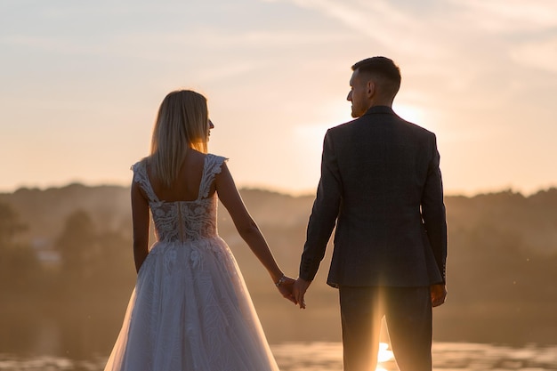 The bride and groom are in the back at sunset