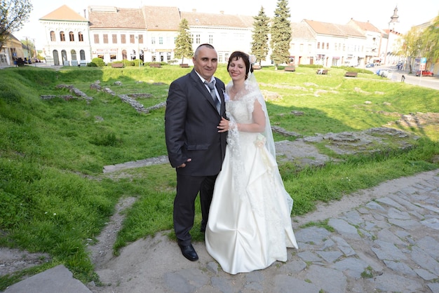 The bride and groom are having fun at their wedding The groom is dressed in a gray suit and the bride in a white silk dress