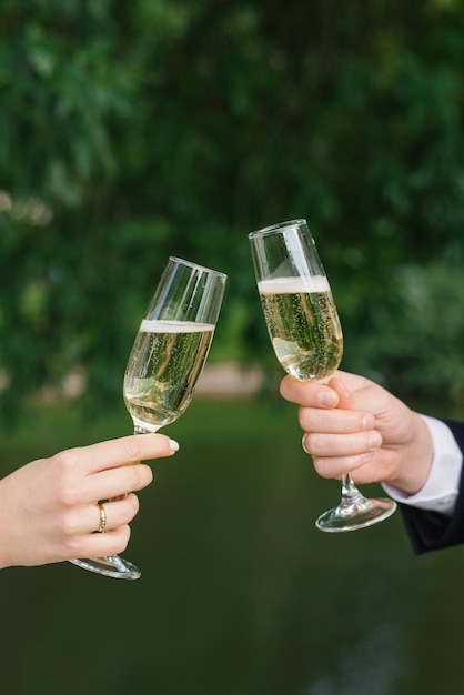 The bride and groom are holding two champagne glasses for the wedding ceremony