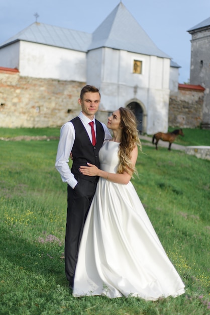 The bride and groom are hugging against the background of the old monastery.