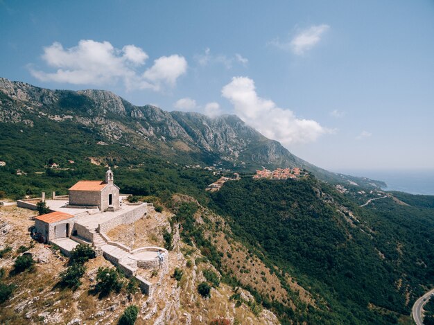 The bride and groom are sitting embracing on the observation deck near the ancient monastery