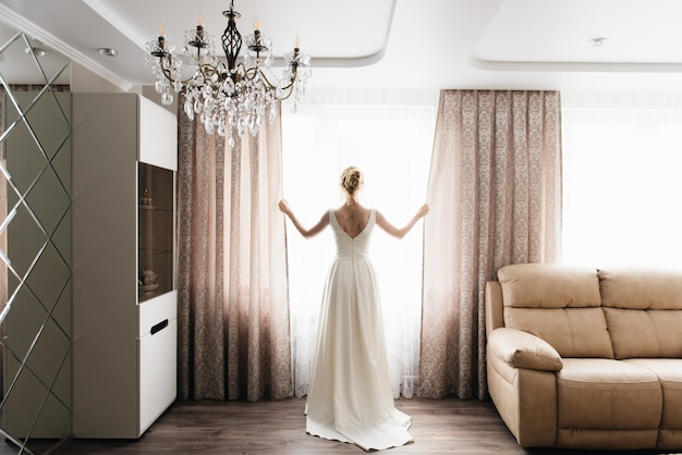 Photo bride and groom are standing against the window looking outside