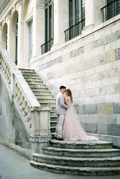 Bride and groom are standing on the stone steps of an old building Bergamo Italy