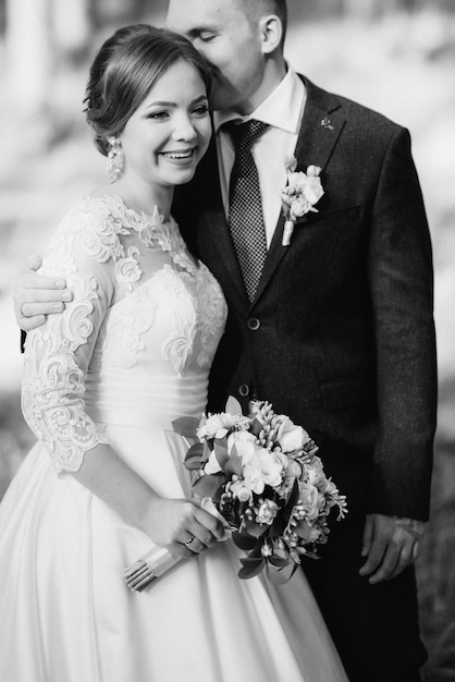 The bride and groom are walking in a pine forest on a bright day