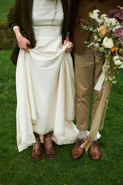 Bride and groom in autumn boots on the grass, showing legs