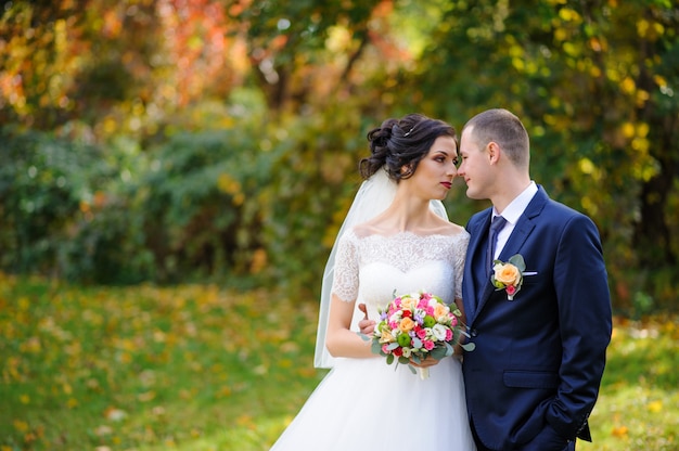 La sposa e lo sposo sullo sfondo del parco in autunno