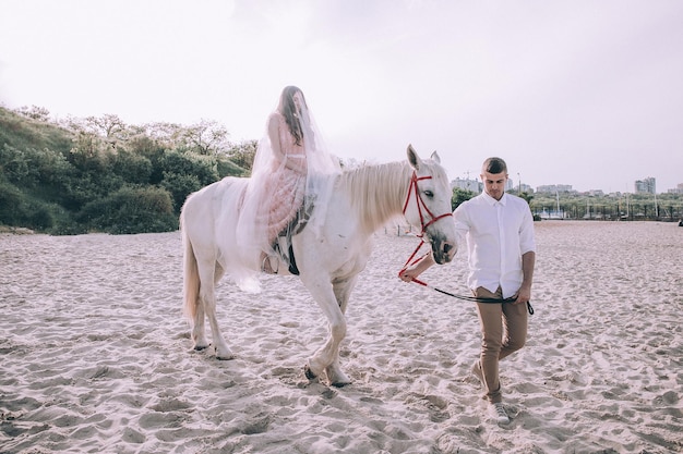 Bride and groom on beach with horses. Wedding couple. Beautiful portrait in nature