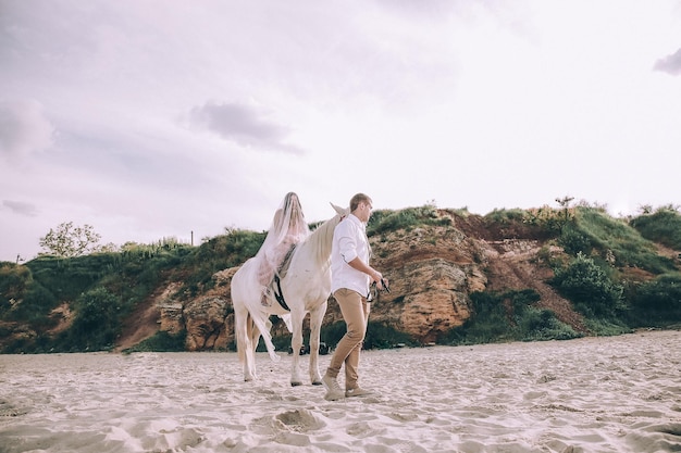 Bride and groom on beach with horses. Wedding couple. Beautiful portrait in nature