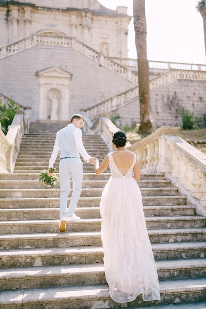 The bride and groom climbing the stairs of the nativity of the blessed virgin mary church in prcanj