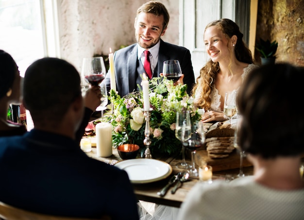 Photo bride and groom clinging wineglasses with friends on wedding reception