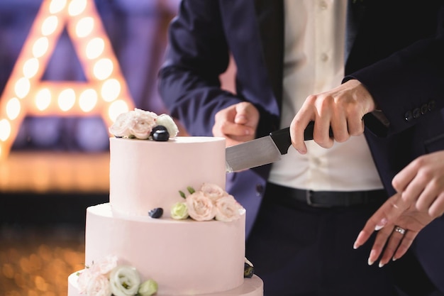 Gli sposi tagliano una splendida torta nuziale durante un banchetto.