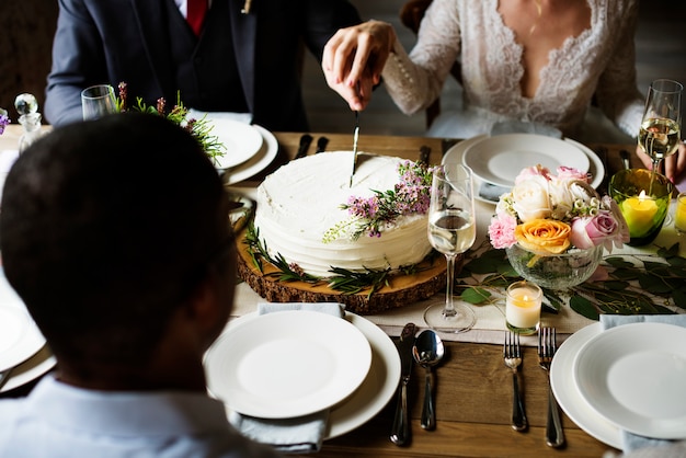 結婚式のレセプションでケーキを切る花嫁と花婿