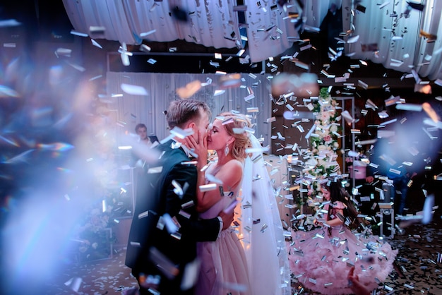 Foto la sposa e lo sposo ballano nella sala piena di fumo e coriandoli nel ristorante