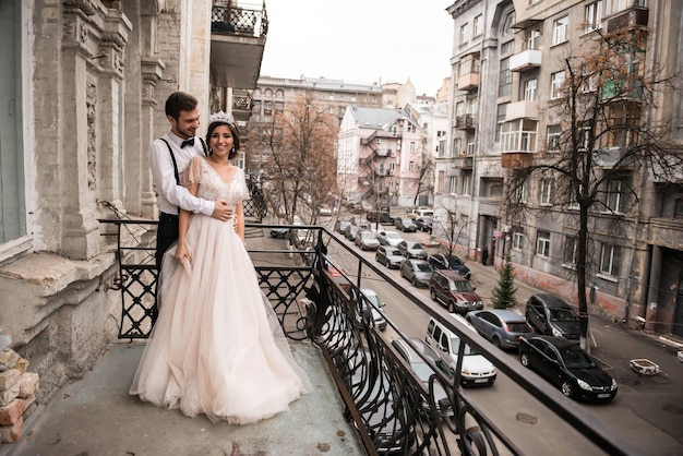 La sposa e lo sposo si abbracciano sul balcone. coppie che abbracciano sul balcone e godersi la vita