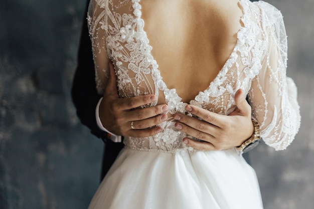 A bride and groom embrace in front of a dark background.