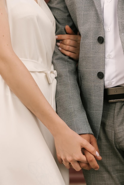 The bride and groom embrace hands closeup