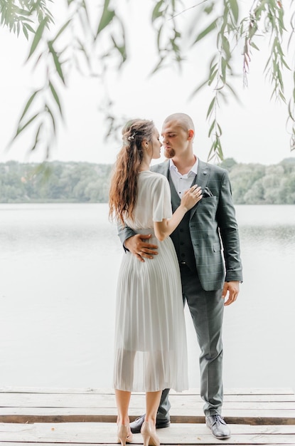 Foto la sposa e lo sposo si abbracciano e si baciano sulla riva del lago.