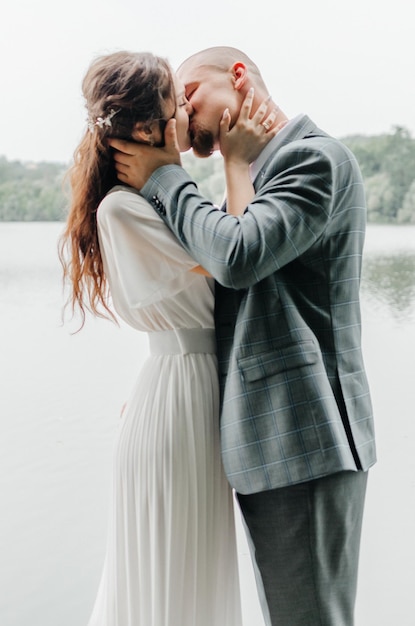 Foto la sposa e lo sposo si abbracciano e si baciano sulla riva del lago.