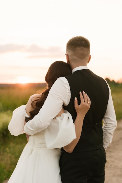 Foto l'abbraccio degli sposi sta in piedi con le spalle al tramonto