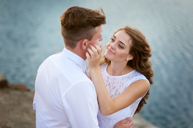 Bride and groom embracing at the lake for a walk.