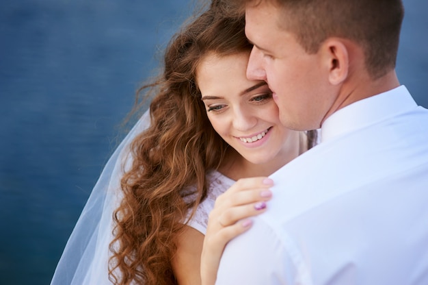 Bride and groom embracing at the lake for a walk.