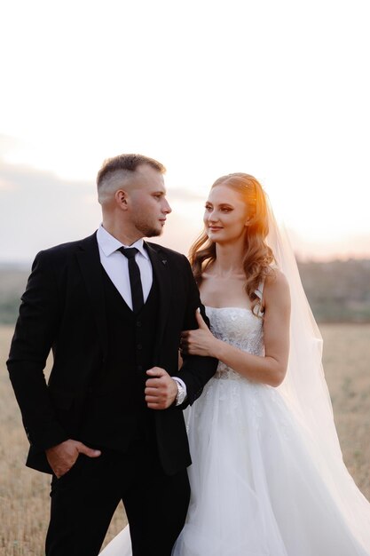 a bride and groom in a field with the sun setting behind them