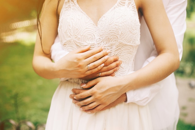 Bride and groom hands close up in the sunny day in the park