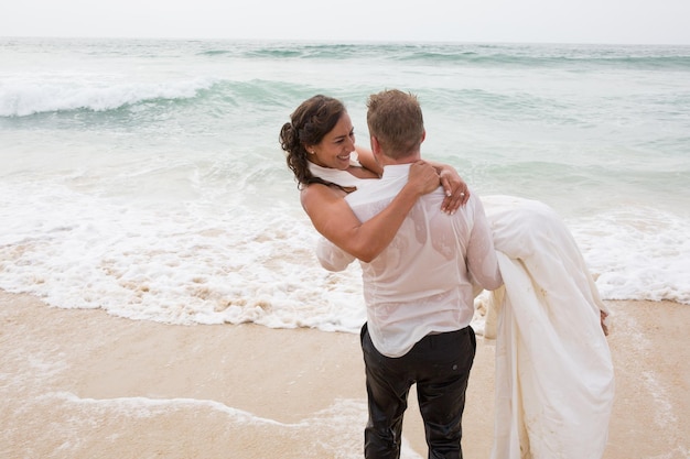 신부와 신랑은 바다 모래 해변에서 결혼식을 즐깁니다.