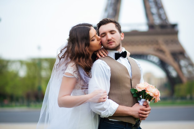 Bride and groom having a romantic moment on their wedding day in Paris, in front of the Eiffel Tower