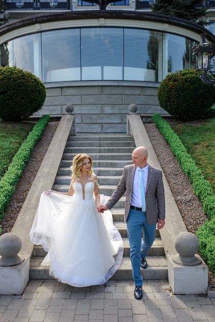 The bride and groom hold hand and go down the stairs.