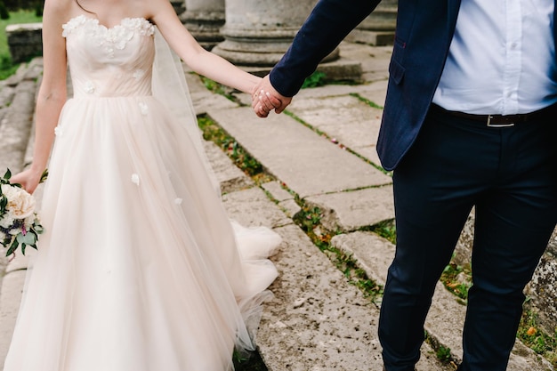 The bride and groom hold hands go down the old stairs near\
antique old castle vintage palace after the wedding ceremony bottom\
view engagement