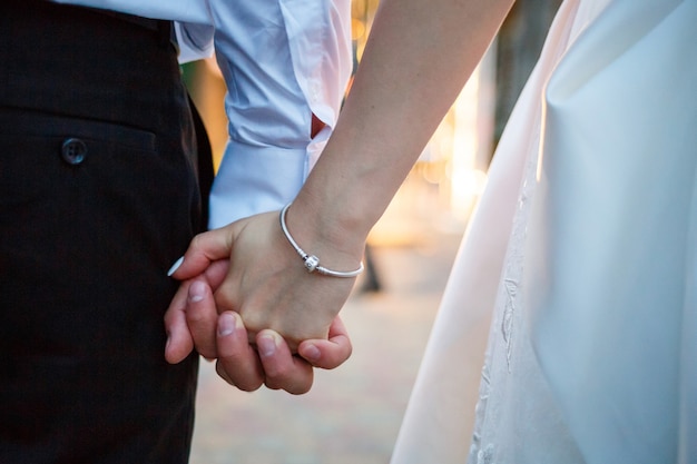 Photo bride and groom hold hands on wedding day