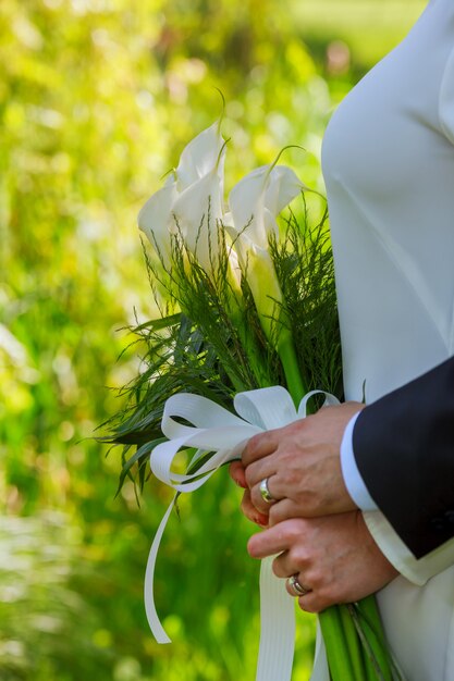 Photo bride and groom holding a bouquet of kala