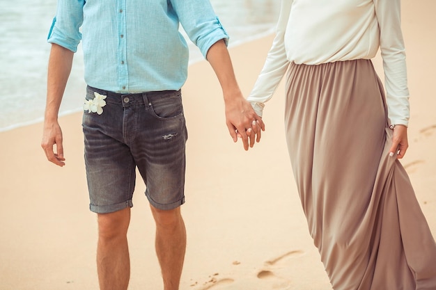 La sposa e lo sposo che si tengono per mano si chiudono in spiaggia. vacanza. phuket. tailandia.