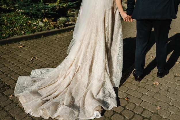 The bride and groom holding hands Engagement Newlyweds of the outdoors The bride and groom go ahead and walking on a stroll along the street in the city Bottom back view