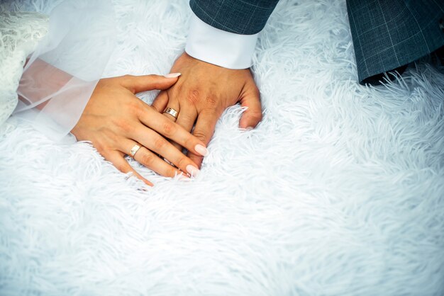 Bride and groom holding hands with woman's hand on man's hand with wedding rings