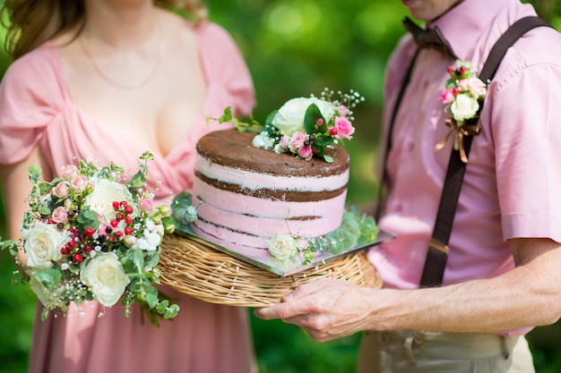 Bride and groom holding a rustic wedding cake