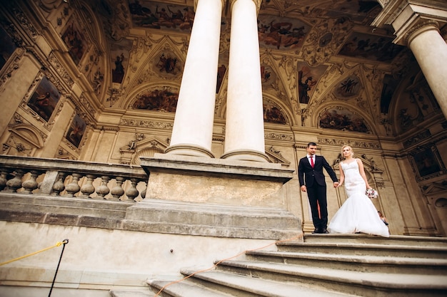 Bride and groom hug, kiss outdoors on wedding day, young couple walk in Prague, valentine's day