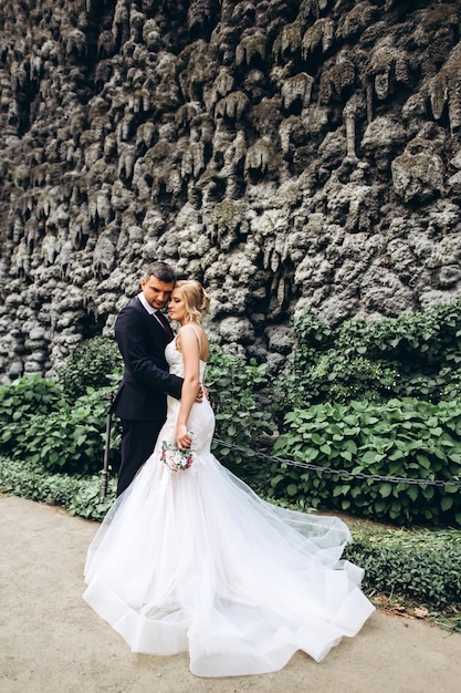 Bride and groom hug, kiss outdoors on wedding day, young couple walk in Prague, valentine's day