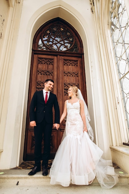 Bride and groom hug, kiss outdoors on wedding day, young couple walk in Prague, valentine's day