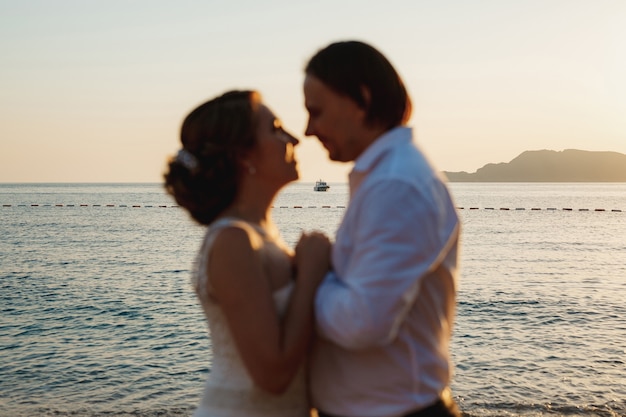 The bride and groom hug on the picturesque seashore, blurred couple. 