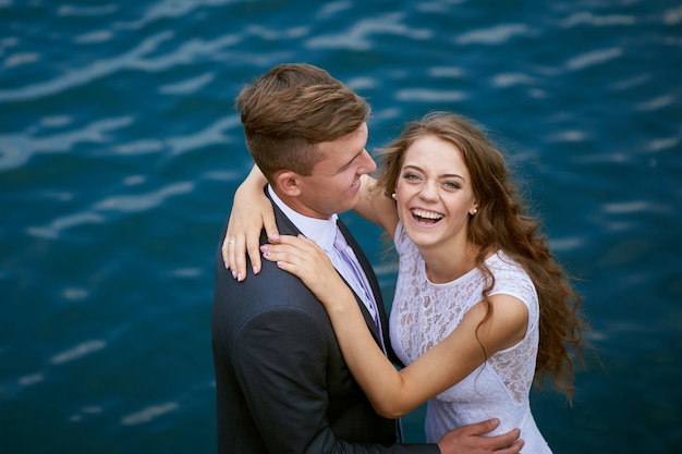 Bride and groom hugging at the background of water