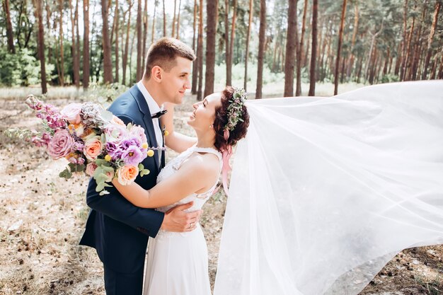 Bride and groom hugging, kissing outdoors on a wedding day, young couple, valentine's day