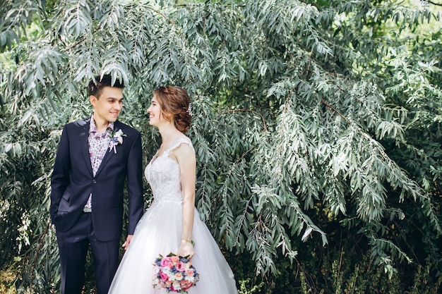 Bride and groom hugging, kissing outdoors on a wedding day, young couple, valentine's day