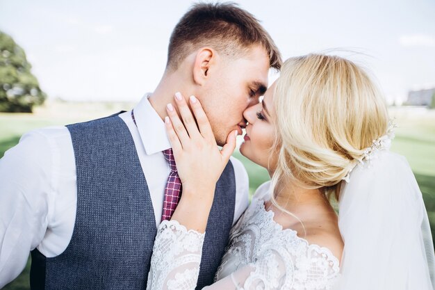 Bride and groom hugging, kissing outdoors on a wedding day, young couple, valentine's day